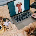 Portable Chargers - From above back view of crop anonymous female remote employee showing photography on netbook screen at table with hot drink